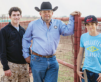 Gene Baker and sons near a fence