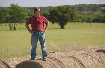Steve Specht stands on circular hay bales
