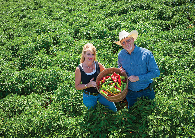 Evelyn and Rick Ledbetter in a chile field with a basket of chiles
