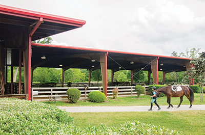 student leading her mount toward the riding arena