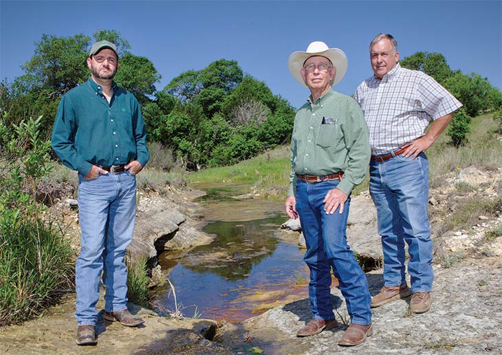 Jule Richmond, center, stands by a spring that feeds into the Pecan Bayou.