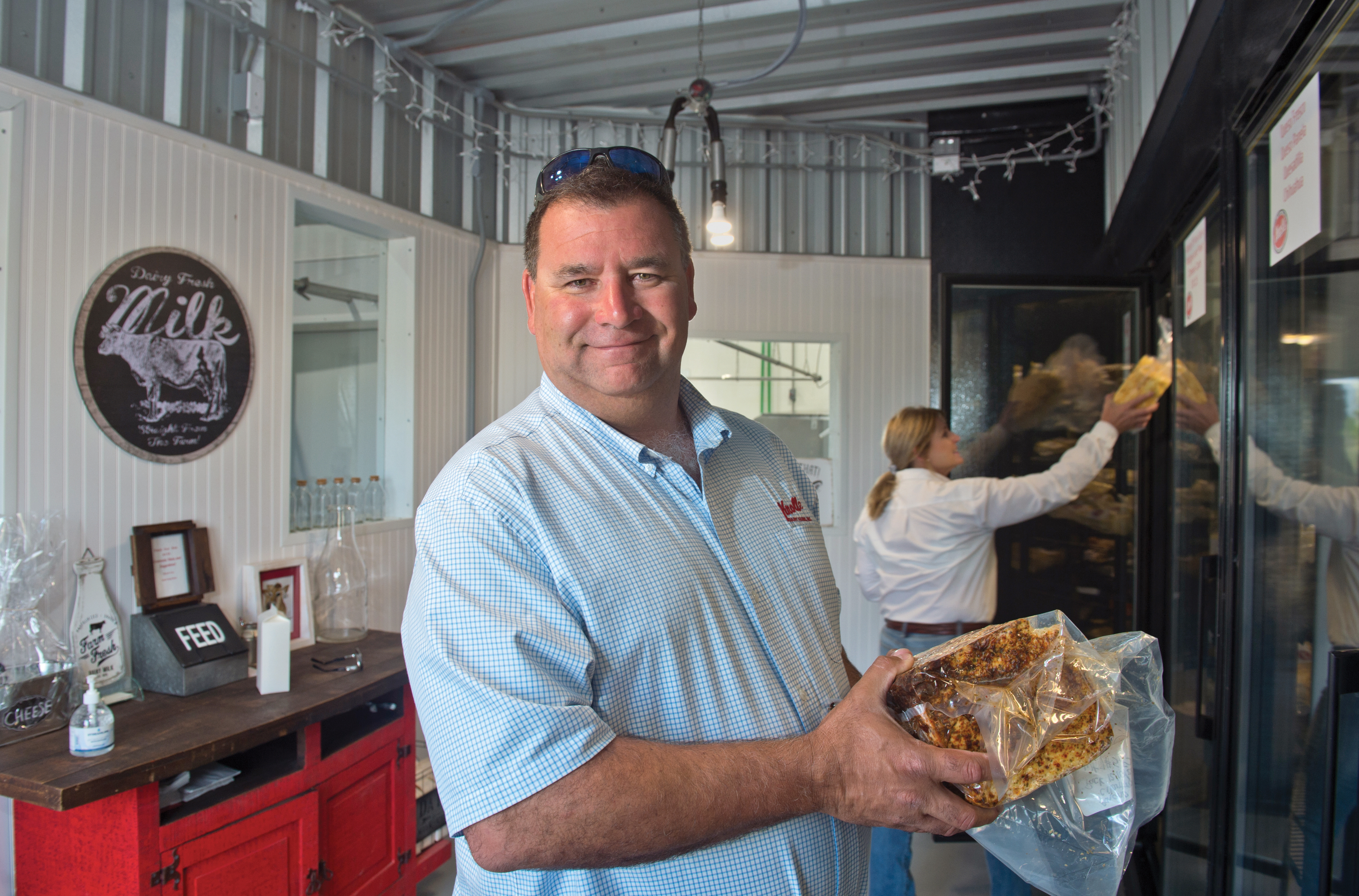 Joe and Christina Knolle stock their farm store coolers with herb-flavored cheeses. Windows, at rear, look out on the processing facility