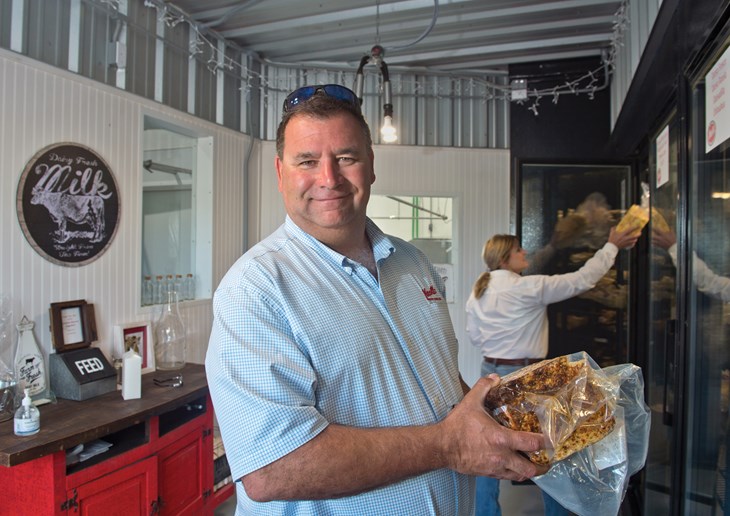 Joe and Christina Knolle stock their farm store coolers with herb-flavored cheeses. Windows, at rear, look out on the processing facility.