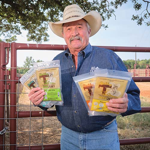 photo of Bob Tallman holding up four different flavors of his Bobby T&#x27;s Beef Jerky