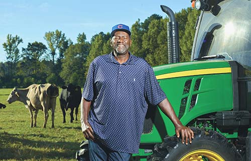 photo of retired legendary MLB relief pitcher Lee Smith in front of his tractor and cattle