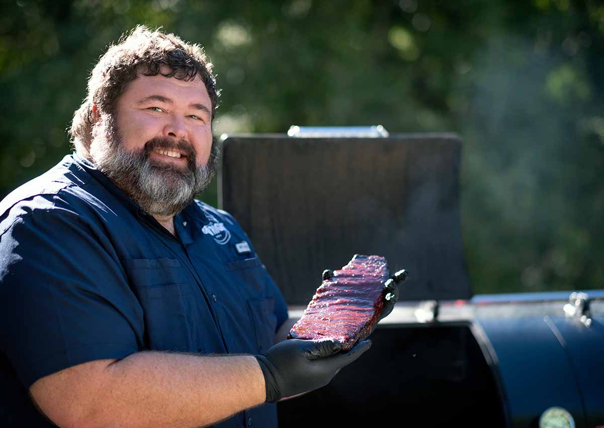 photo of barbecue pro Malcom Reed cradling a rack of his award-winning ribs, hot off the pit