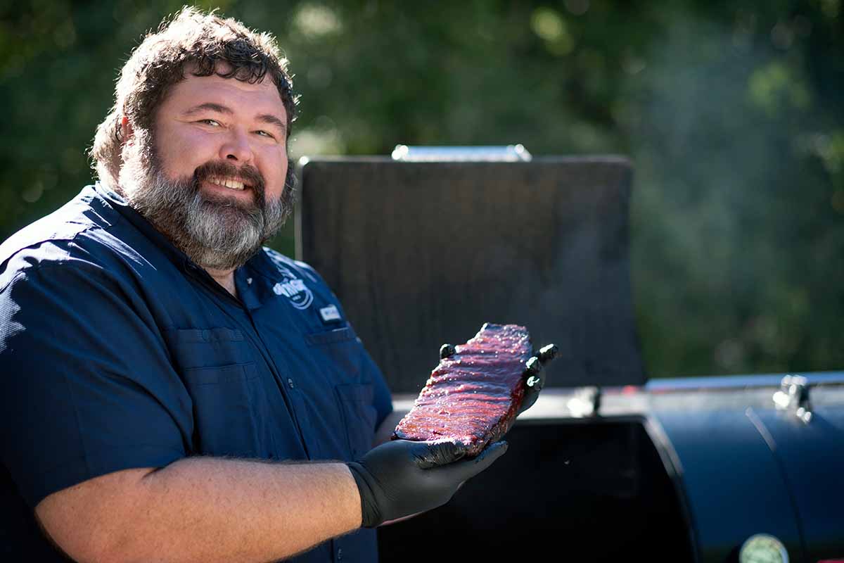 photo of barbecue pro Malcom Reed cradling a rack of his award-winning ribs, hot off the pit