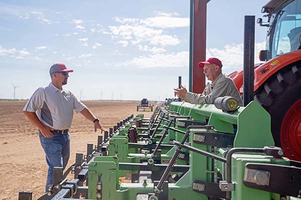 Carl Pepper and Travis Ferguson talking next to customized farm equipment
