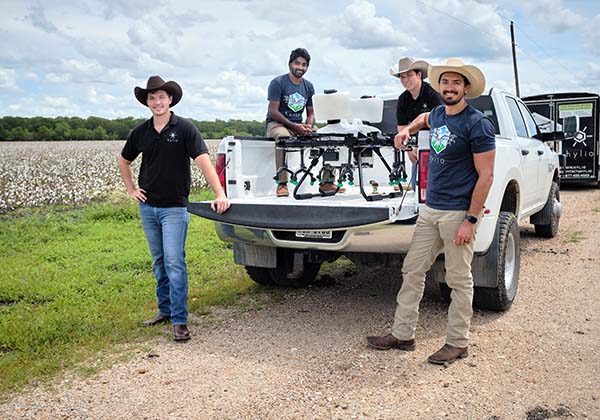 Hylio Inc.&#x27;s team stands with their equipment out near a cotton field