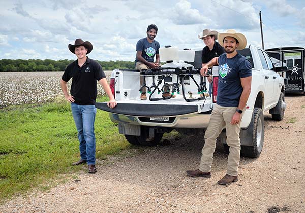 Hylio Inc.'s team stands with their equipment out near a cotton field