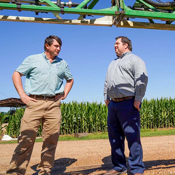 Jonathan Wright and Kody Beavers stand next to field and equipment